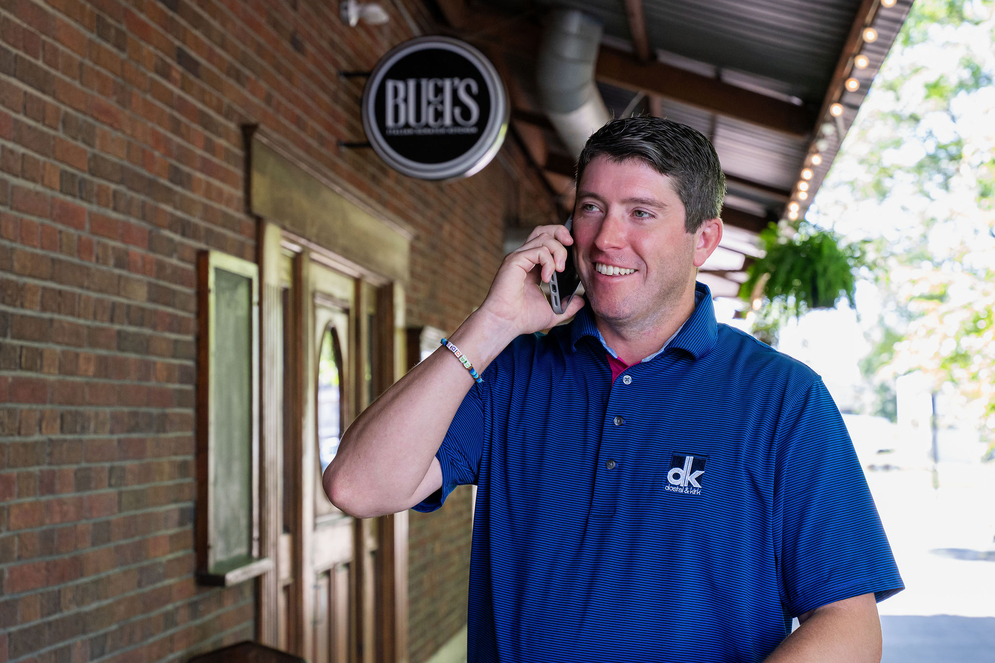 Dostal & Kirk team member in a blue polo shirt talking on the phone