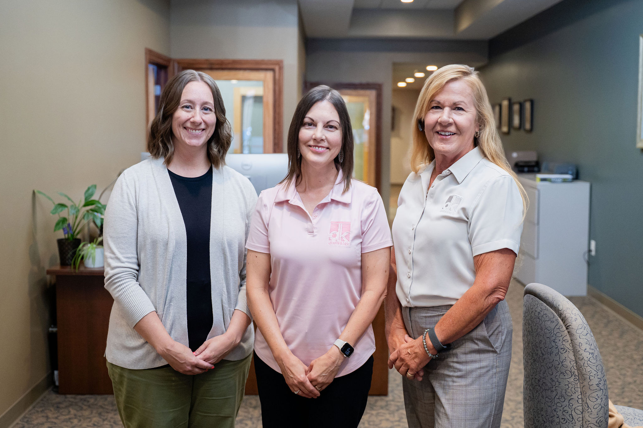 Dostal & Kirk team members standing together in the office hallway, smiling at the camera.