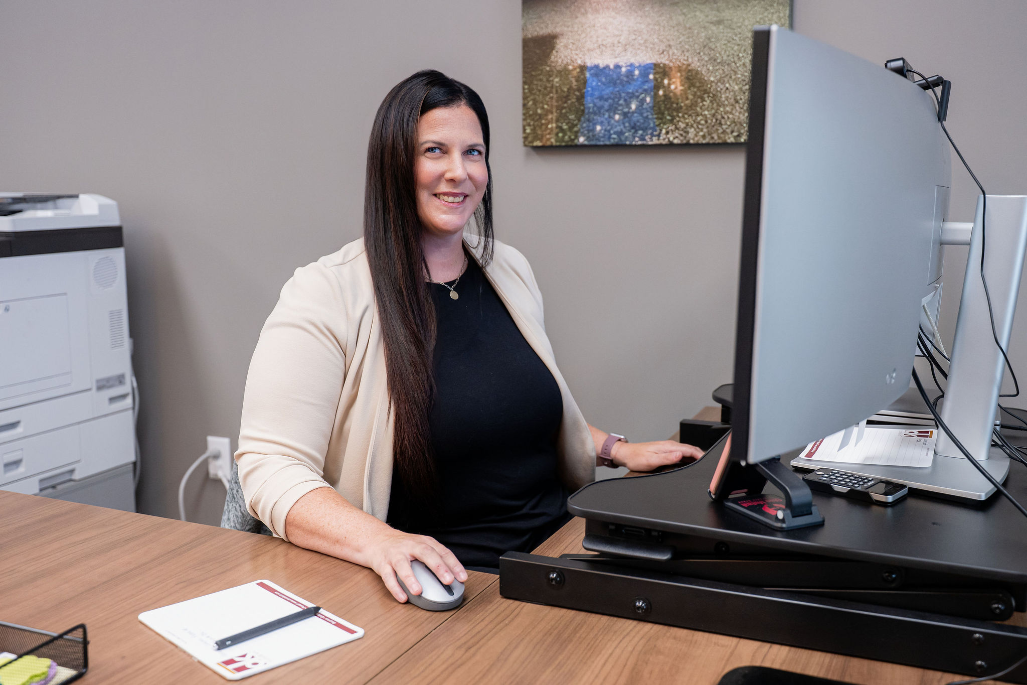 Team member working at her desk and smiling, representing professional and client-focused support